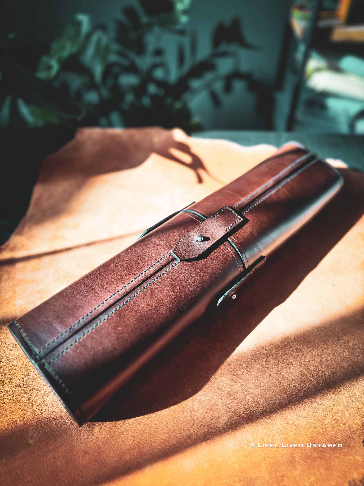 Brown leather tool-roll on a leather skin surface showing details of saddle stitches