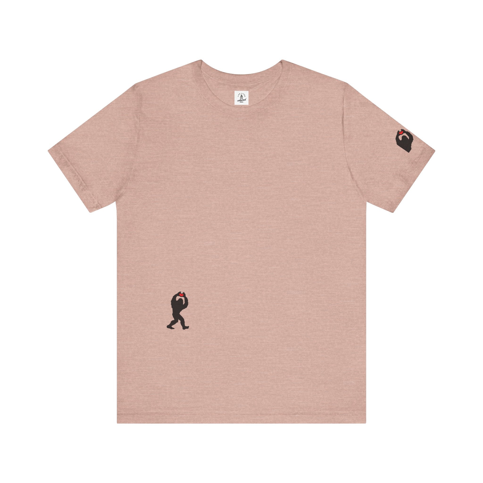 Women's peach t-shirt with small black Sasquatch graphic on lower front and a sleeve on a white background