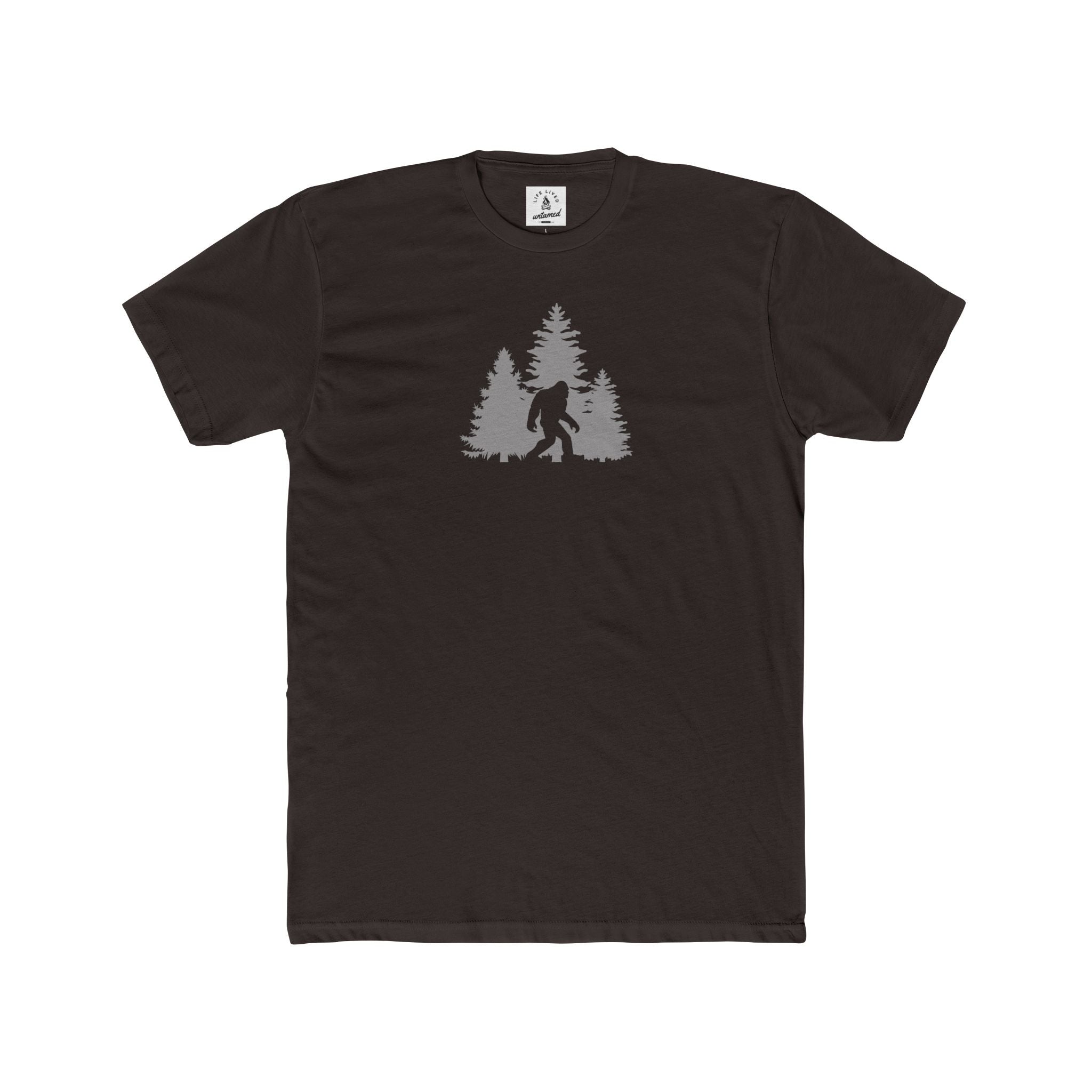 Dark chocolate t-shirt with a graphic of a forest and a bigfoot silhouette on a white background