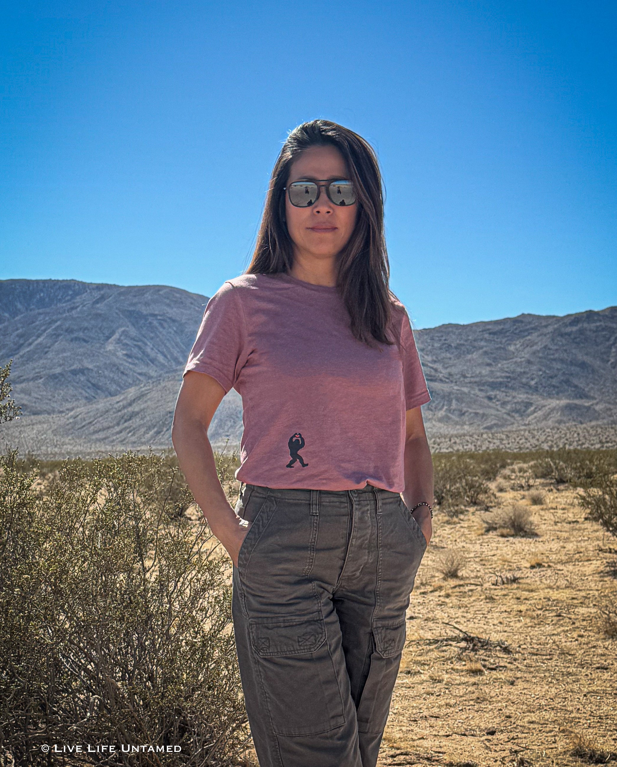 Person standing in a desert landscape wearing a tee with Bigfoot holding heart