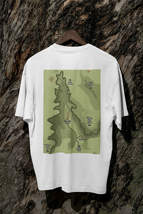 White t-shirt with a green map design on a wooden hanger against a textured brown background