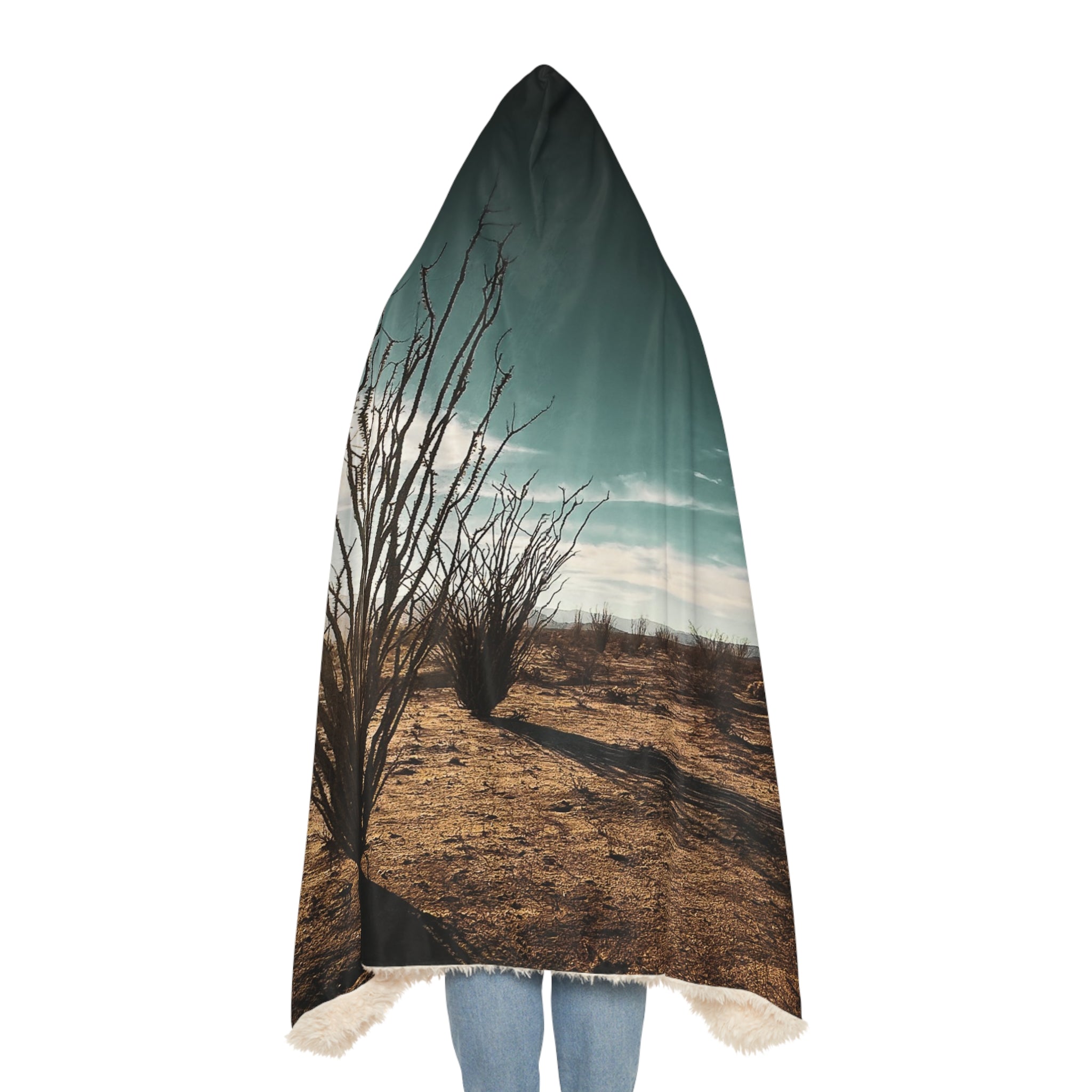 Backside of hoodie blanket with desert landscape design draped over a person
