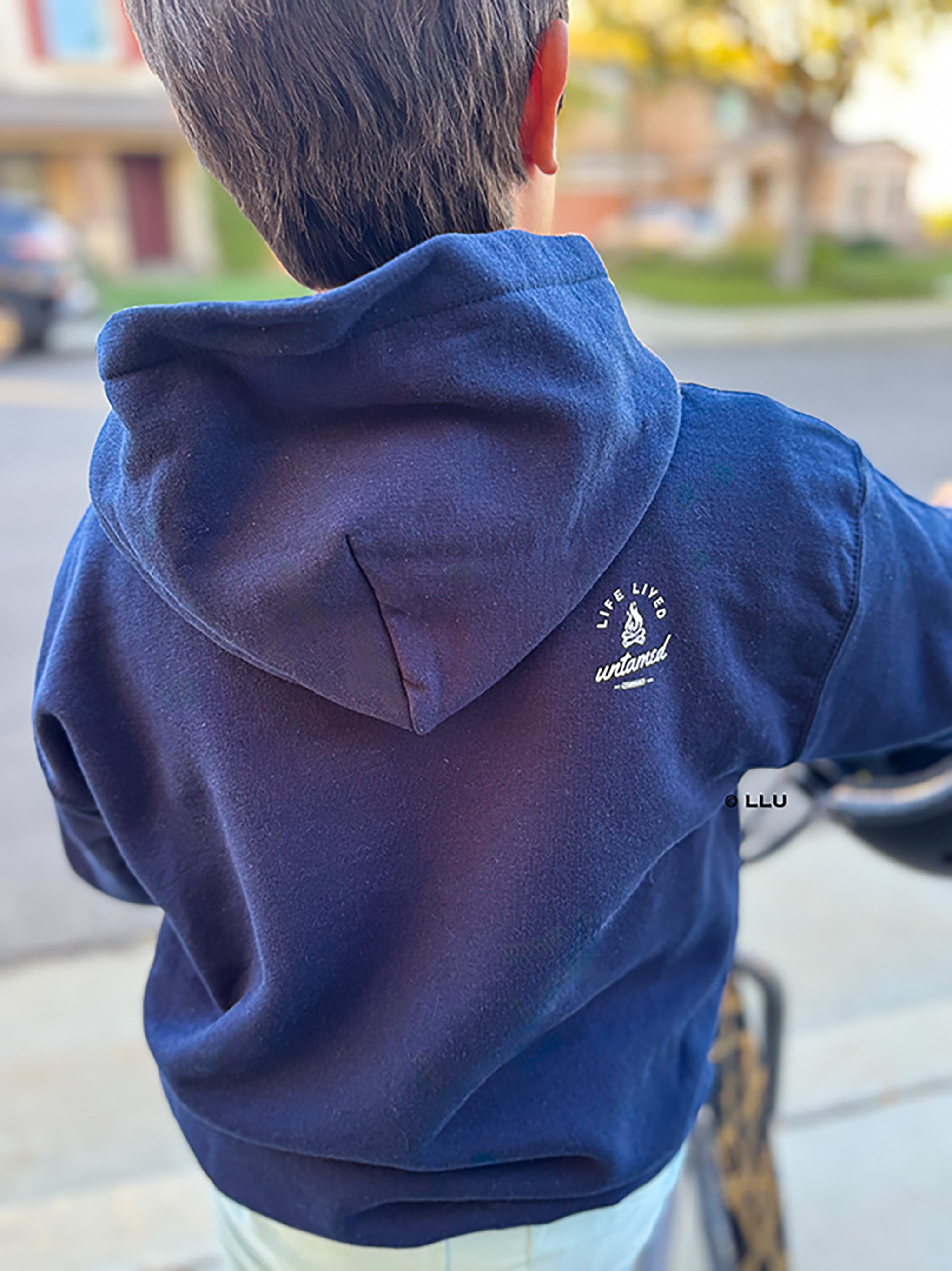 Chance wearing a blue hoodie with a logo on the back, standing outdoors.