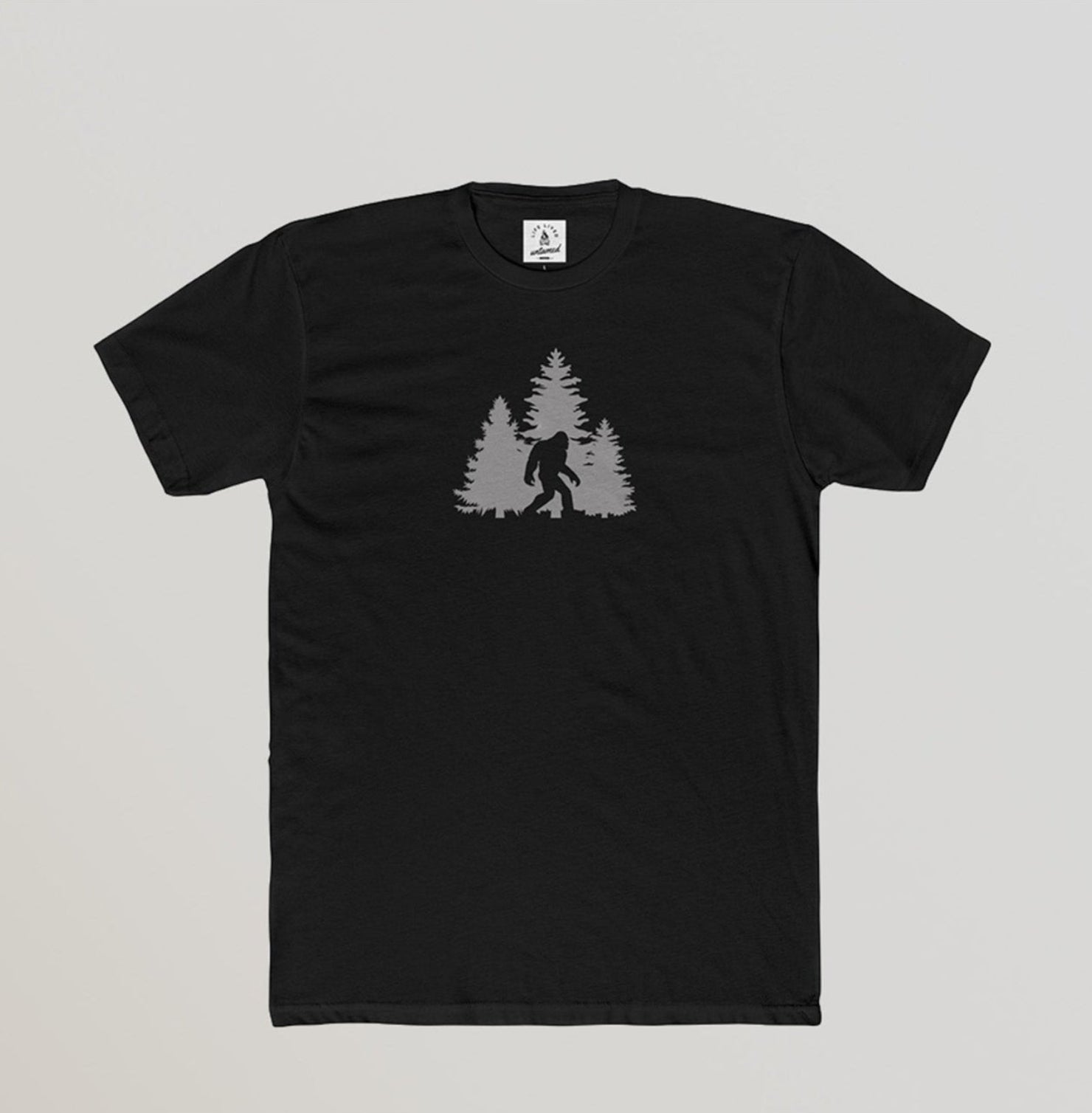 Black t-shirt with a graphic of a silhouette of a bigfoot and trees
