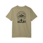 Khaki t-shirt with a graphic design on the back featuring mountains, trees, and a silhouette of a Sasquatch