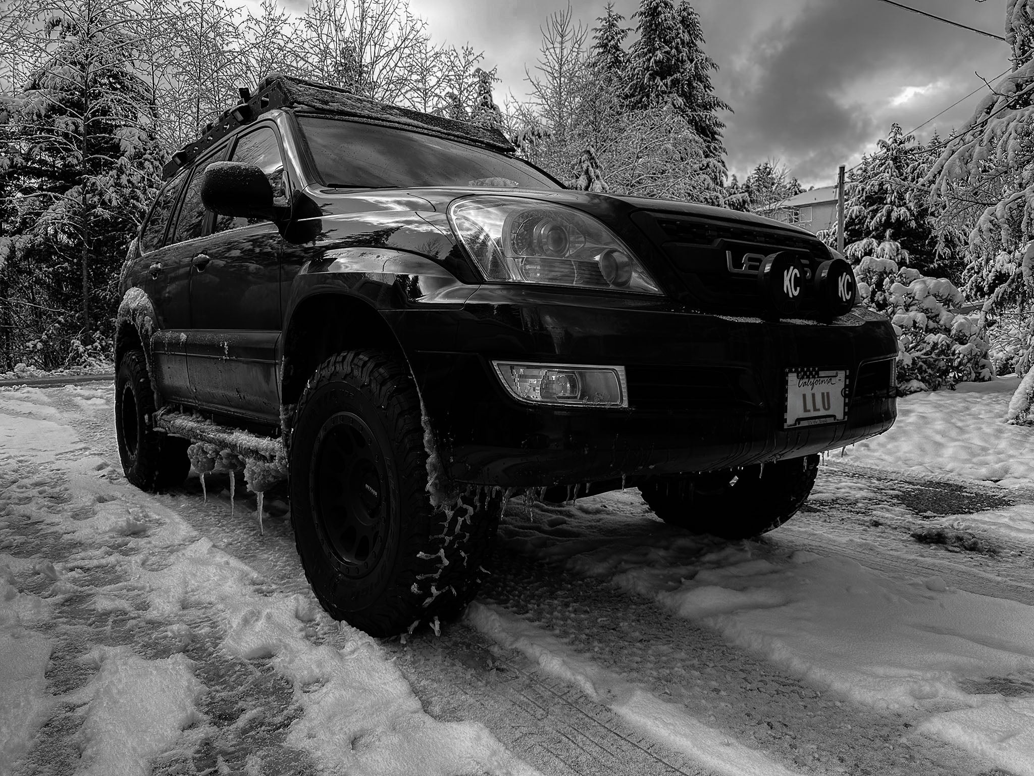 Black SUV on a snowy road with trees in the background