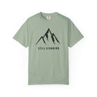 Bay green t-shirt with a mountain graphic and 'STILL STANDING' text on a white background