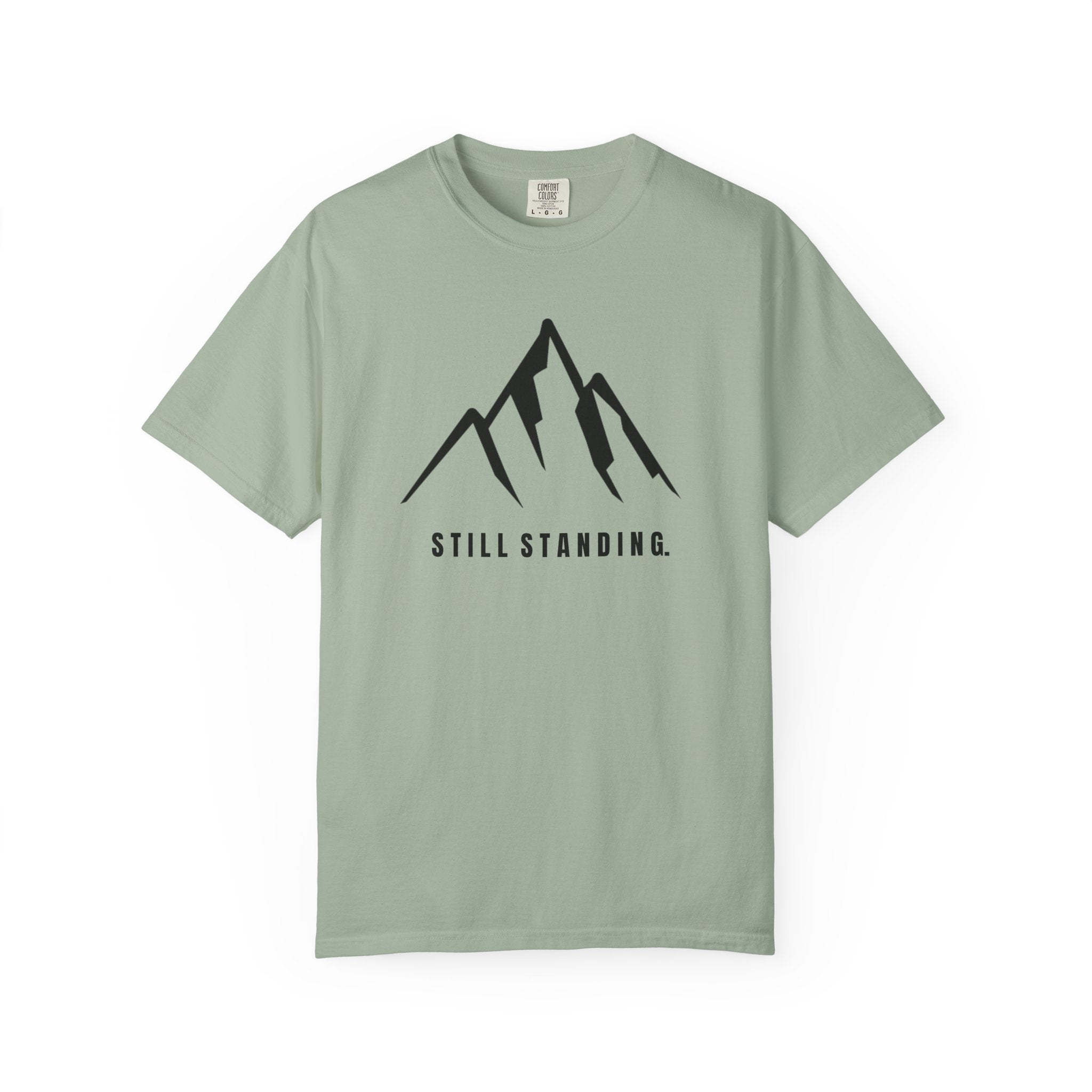 Bay green t-shirt with a mountain graphic and 'STILL STANDING' text on a white background