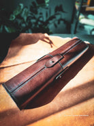 Brown leather tool-roll on a leather skin surface showing details of saddle stitches