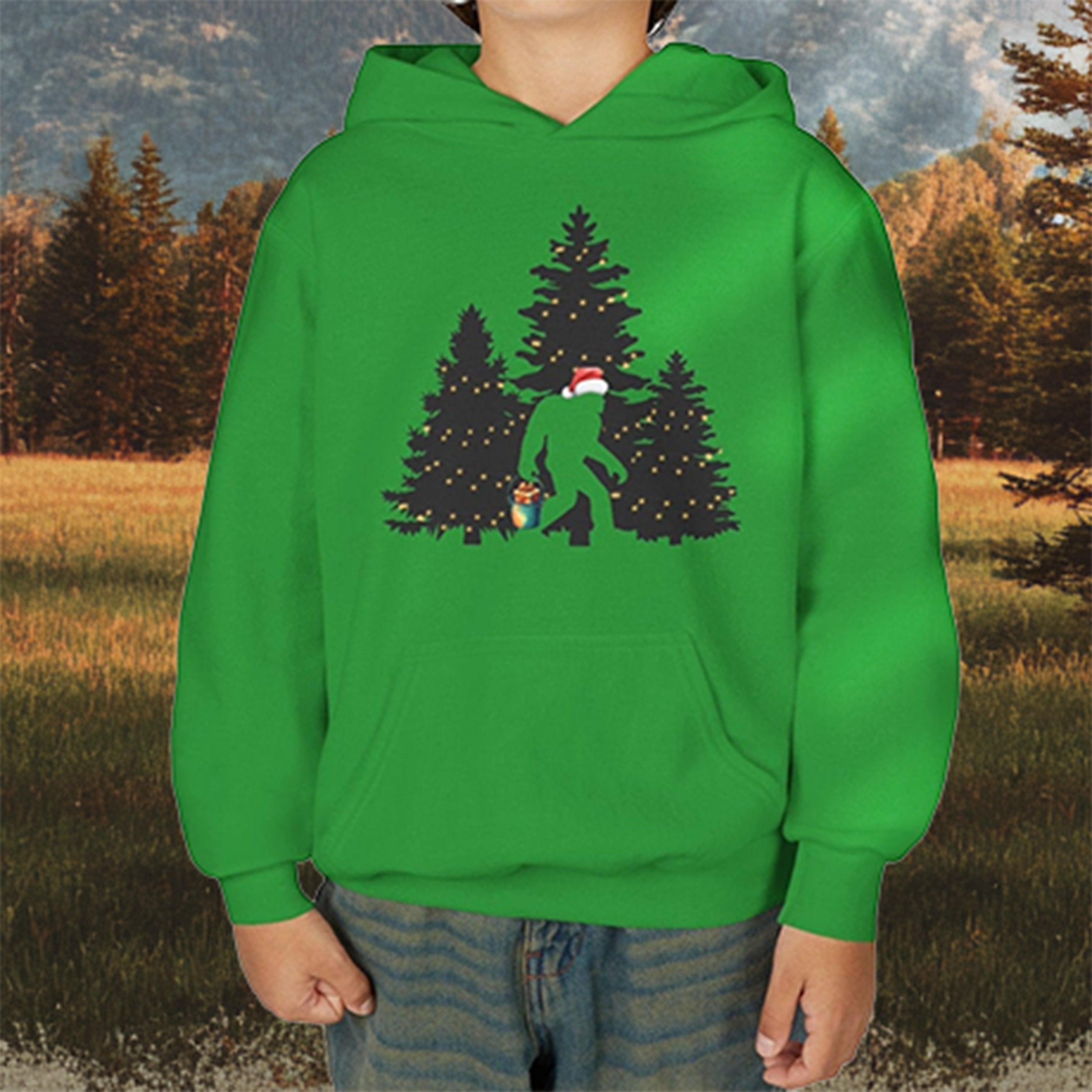 A close up picture of green hoodie with a big foot wearing a Christmas hat and carrying a bucket of present in the woods in Yellowstone National Park background. 