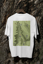 White t-shirt with a green map design on a wooden hanger against a textured brown background