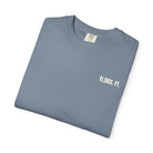 Folded denim blue t-shirt with '11,503. FT.' text on a white background