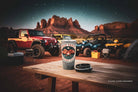 Jeep vehicles parked in a desert landscape with a starry night sky, featuring a coffee cup on a wooden table.